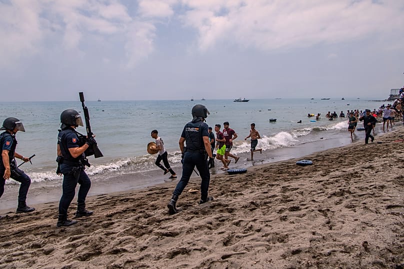 Spanish police officers respond as migrants cross from Morocco into the Spanish enclave of Ceuta