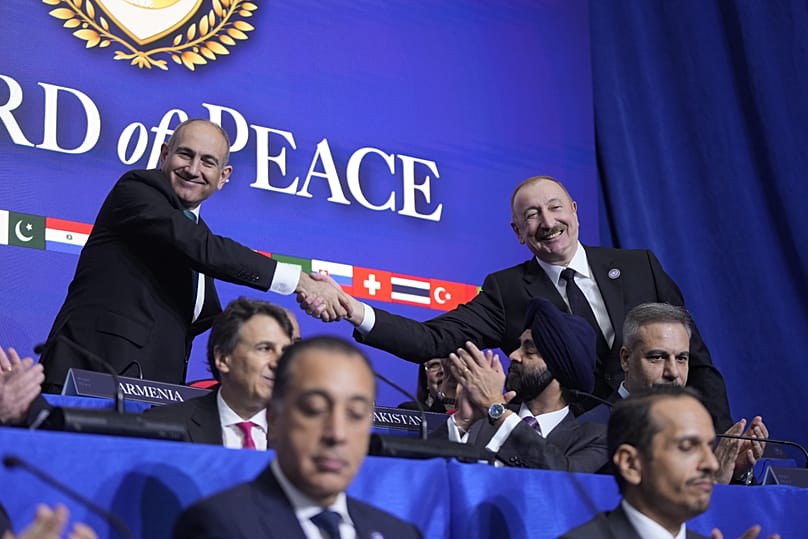 Armenia's Prime Minister Nikol Pashinyan, left, and President of Azerbaijan, Ilham Aliyev, right, shake hands during a Board of Peace meeting in Washington, February 2026