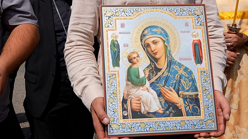 A person holds a religious icon depicting the Virgin Mary and the Christ Child alongside other saintly figures, in Gandzasar, 21 September 2026