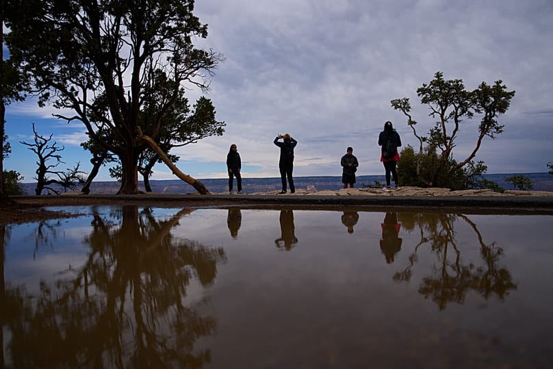 People stand at the rim of the Grand Canyon