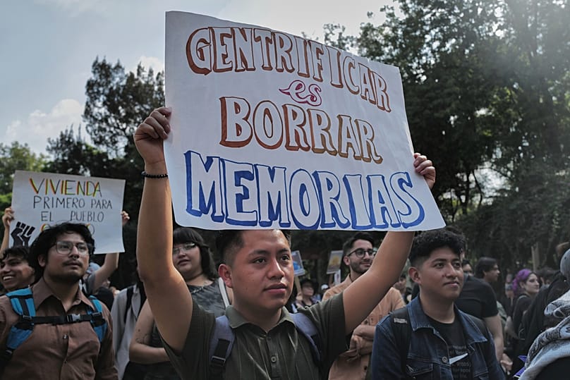 A Mexican man holds a sign reading 