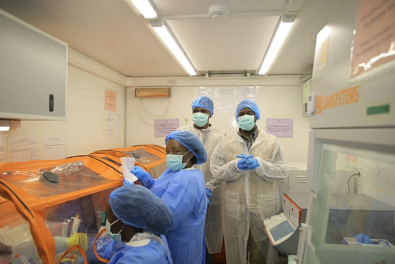 Medical workers work inside a mobile lab set up to test rapidly for Ebola virus in Butembo, DR Congo.