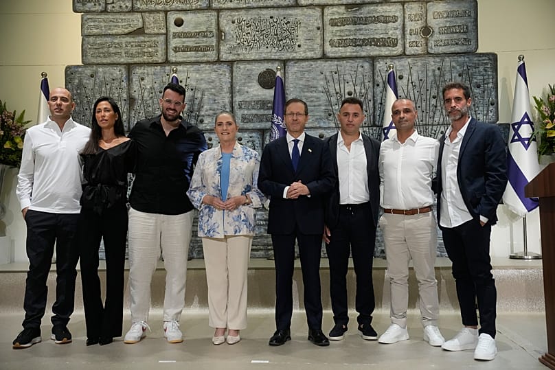Israeli President Isaac Herzog and his wife Michal pose with six passengers awarded for helping save lives aboard a Flydubai flight from Dubai to Tel Aviv, in Jerusalem, 8 Oct