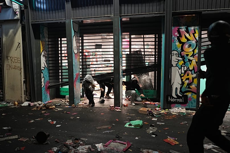 Protesters emerge from a looted store during a demonstration against rising living costs, joining students' grievances, in Paris, Saturday, Oct. 17, 2026.